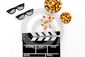 To go to the cinema. Clapperboard, glasses and popcorn on white background top view