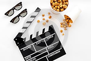 To go to the cinema. Clapperboard, glasses and popcorn on white background top view