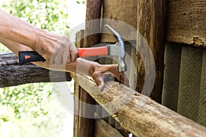 To hammer a nail with a hammer. Older worker carpenter