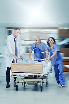 To the operating room stat. Shot of a group of medical professionals rushing a patient on a gurney down a hospital