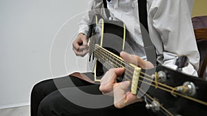 To play guitar. Strumming on an acoustic guitar. The musician plays music. A man plays the guitar in a bright room. An