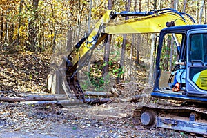 To prepare for construction home builder uses a tractor to uproot trees in forest photo