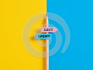 To save or to spend choice or decision. Pencil with direction indicator stickers showing the different decision paths to save or