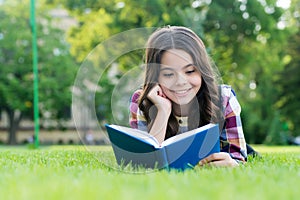 To succeed you must read. Happy kid read book lying on green grass. School library. Literacy education. Home reading