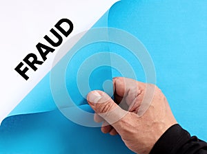 To uncover fraud. Male hand opens the blue paper and reveals the word fraud