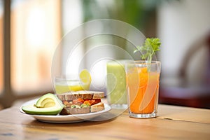 toast with avocado, glass of carrot juice brunch setup