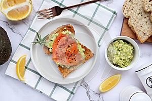 Toast with avocado and smoked salmon and some ingredients at top view