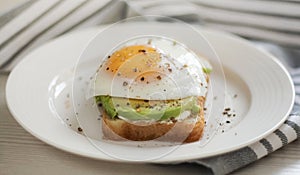 Toast with avocado on a white plate, made from whole grain bread, fried egg side view