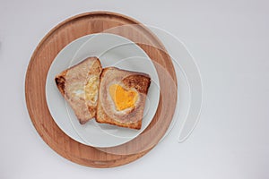 Toast bread with fried egg in a heart shaped hole on plate on white background. Creative Valentine\'s day
