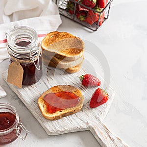 Toast bread with homemade strawberry jam and fresh berries on white background. Summer breakfast with crunchy toasts and