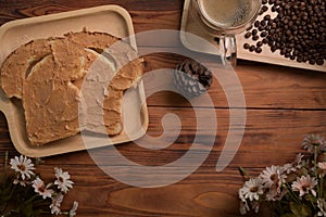 Toast bread with peanut butter and coffee cup on wooden table.