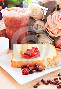 toast bread and sweet strawberry and berry jam in white dish beside cool choclolate on table top ready to eat