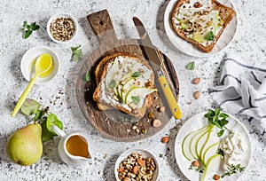 Toast with cheese, pear, honey and nuts. Delicious breakfast or snack on a light background