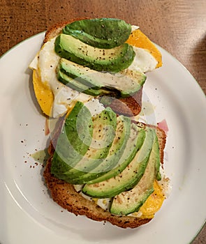 Toast, egg and avacado sandwich on a white plate