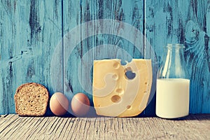 Toast, eggs, cheese and milk on a rustic wooden table, with a fi