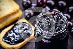 Toast with grape jam, on rustic wooden table. Jabuticaba, exotic Brazilian fruit, used in cooking, as a sweet