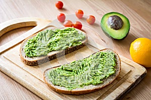 Toast with mashed avocado on wooden cutting board