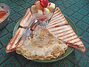 Toast, omlet, fruit salad on table