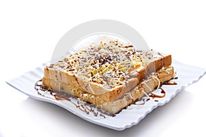 Toast on a plate. Burnt bread sprinkled with chocolate sprinkles, grated cheese, and sweetened condensed milk. Isolated on a white