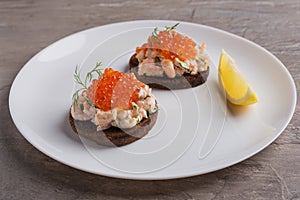 Toast skagen - classic Swedish appetizer. Sandwiches with shrimps and caviar on white plate. Nordic cuisine