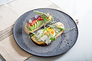 Toast with veggies,avocado, aragula, basil, tomato, mozzarella cheese and sunny side up egg