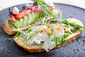 Toast with veggies,avocado, aragula, basil, tomato, mozzarella cheese and sunny side up egg