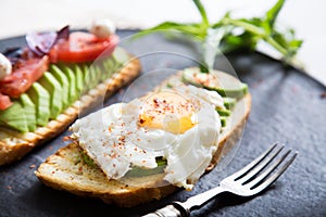 Toast with veggies,avocado, aragula, basil, tomato, mozzarella cheese and sunny side up egg