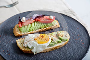 Toast with veggies,avocado, aragula, basil, tomato, mozzarella cheese and sunny side up egg