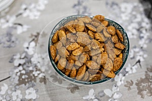 Toasted almonds on a bowl on a table with floral black and white decoration