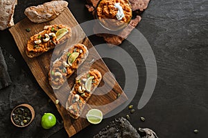 Toasted bread bruschetta with vegetable caviar made of squash pumpkin with green pepper, nuts, lime on wooden cutting board on