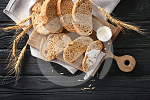 Toasted bread with cream cheese on wooden board, top view