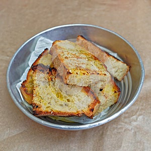Toasted bread with olive oil and oregano in metallic bowl