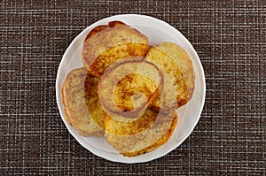 Toasted bread in white plate on mat. Top view