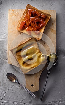 Toasted breads served with honey and jam on cutting board with spoons.