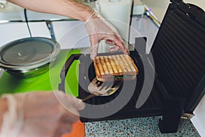 Toasted cheese and ham sandwich with grill marks  on black non-stick grill. Top view.