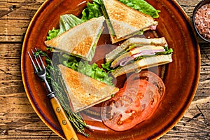 Toasted Club sandwiches with pork ham, cheese, tomatoes and lettuce on a plate. wooden background. Top view