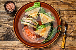 Toasted Club sandwiches with pork ham, cheese, tomatoes and lettuce on a plate. wooden background. Top view