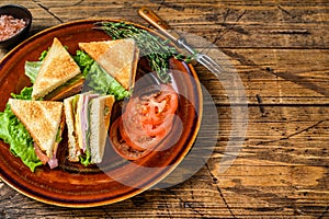 Toasted Club sandwiches with pork ham, cheese, tomatoes and lettuce on a plate. wooden background. Top view. Copy space
