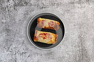 Toasted hot dog wraps on a round plate on a dark gray background