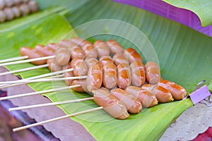 Toasted meatballs on a wooden stick placed on banana leaves