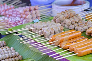 Toasted meatballs on a wooden stick placed on banana leaves