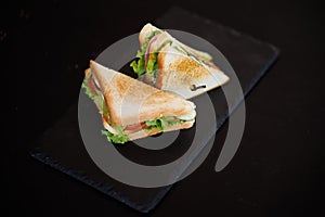 Toasted Sandwich With Lettuce, Tomato, Cheese and Ham, Triangular Slices on Slate Surface
