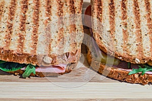 Toasted sandwiches with ham, cheese, tomatoes and salad on wooden cutting board