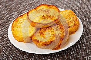 Toasted slices of bread in white plate on dark mat