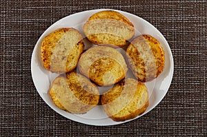 Toasted slices of bread in white plate on mat. Top view