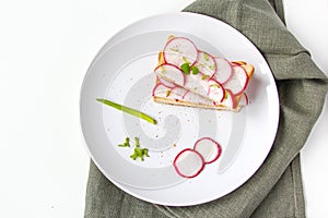 Toasted toast with fresh chopped radishes and green herb on the white plate. Healthy breakfast. Sandwich with vegetable.