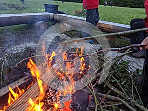 Toasting 2 marshmallows on the end of sticks over a fire