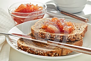 Toasts with apple jam and cup of coffee on white background. Selective focus on toast with jam