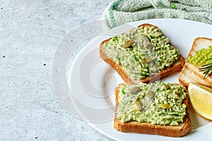 Toasts with avocado paste with sesame seeds on plate on a gray background. The concept of a vegetarian healthy