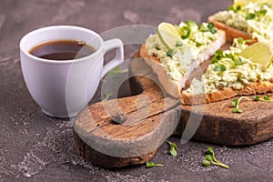 Toasts with avocado pate, fresh microgreen and cup of coffee